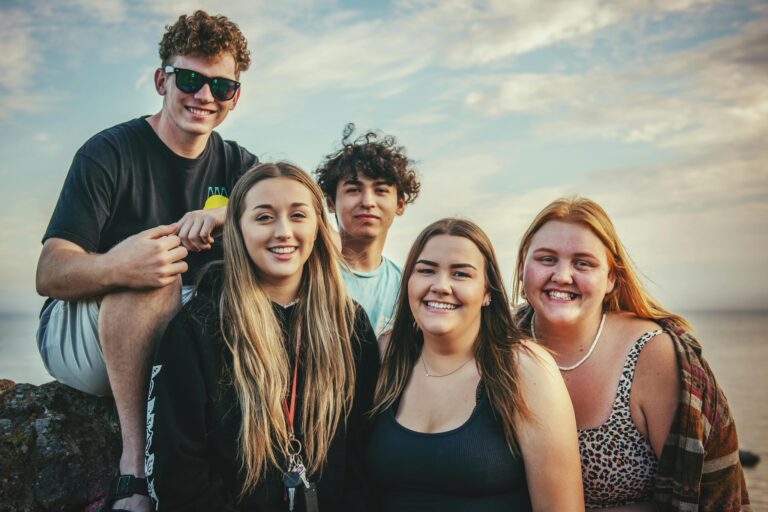 Happy young friends posing and smiling together at Avila Beach, California during a sunny day.